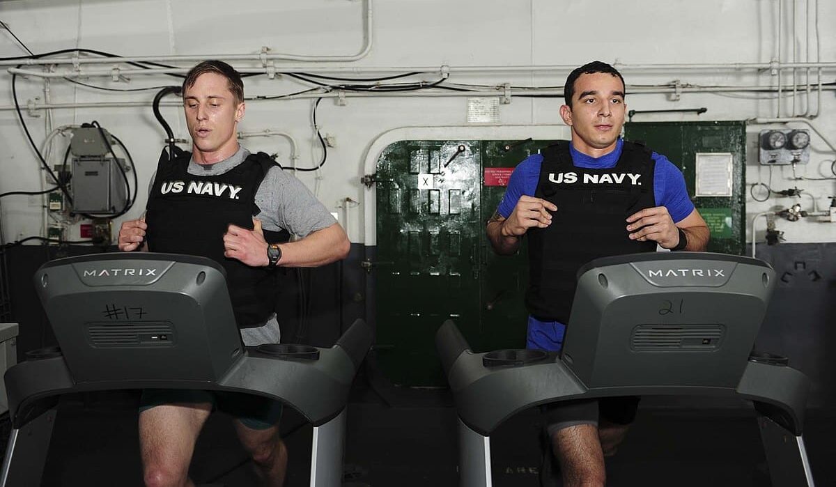 Two mans wearing weights on treadmill