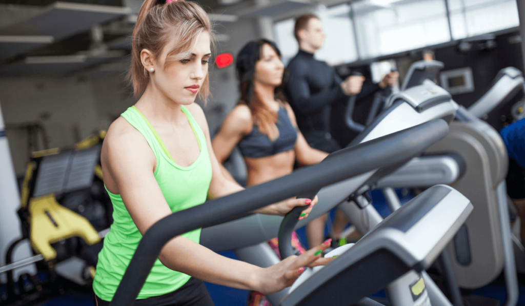 A group of people working out at the gym on treadmills and stair climbers