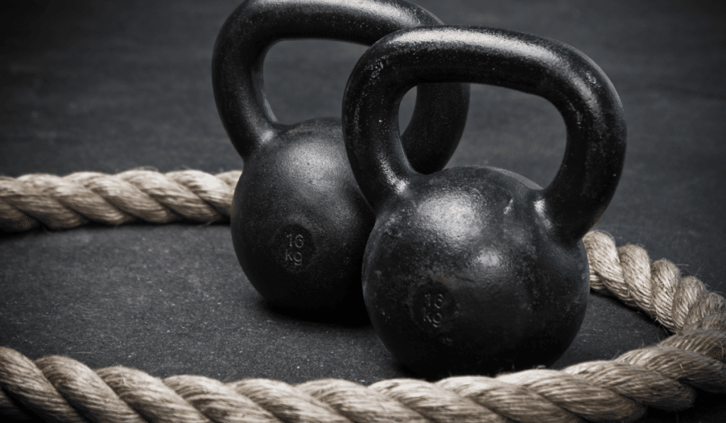 Two 16 kg kettlebells and a rope on gym flooring