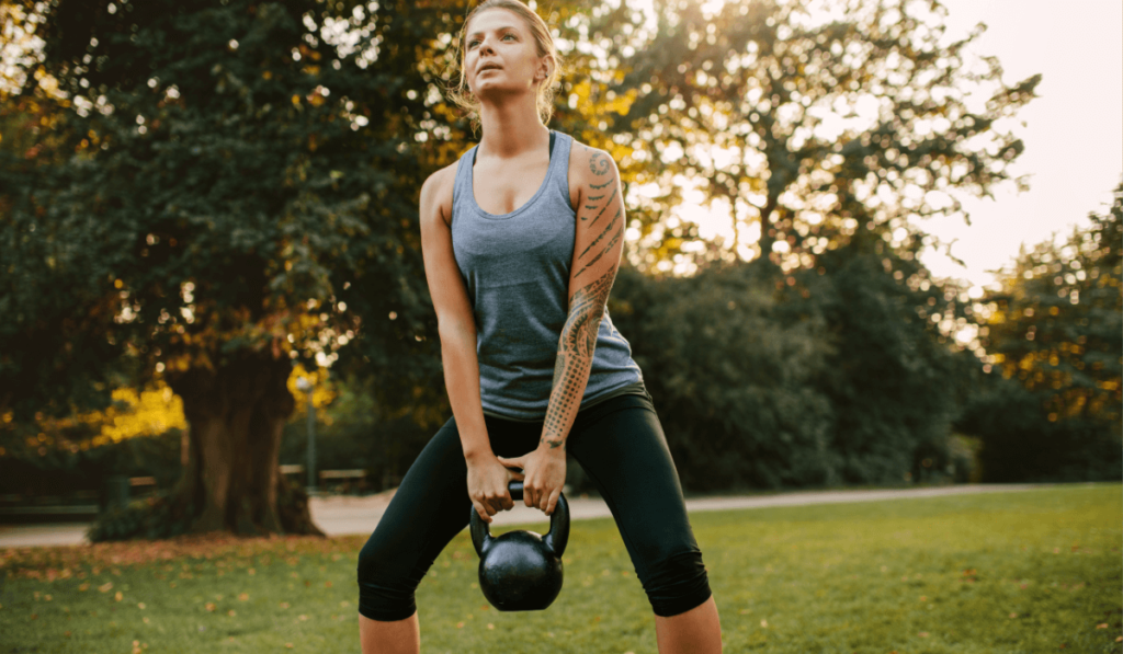 A woman doing beginner kettlebell exercises outside