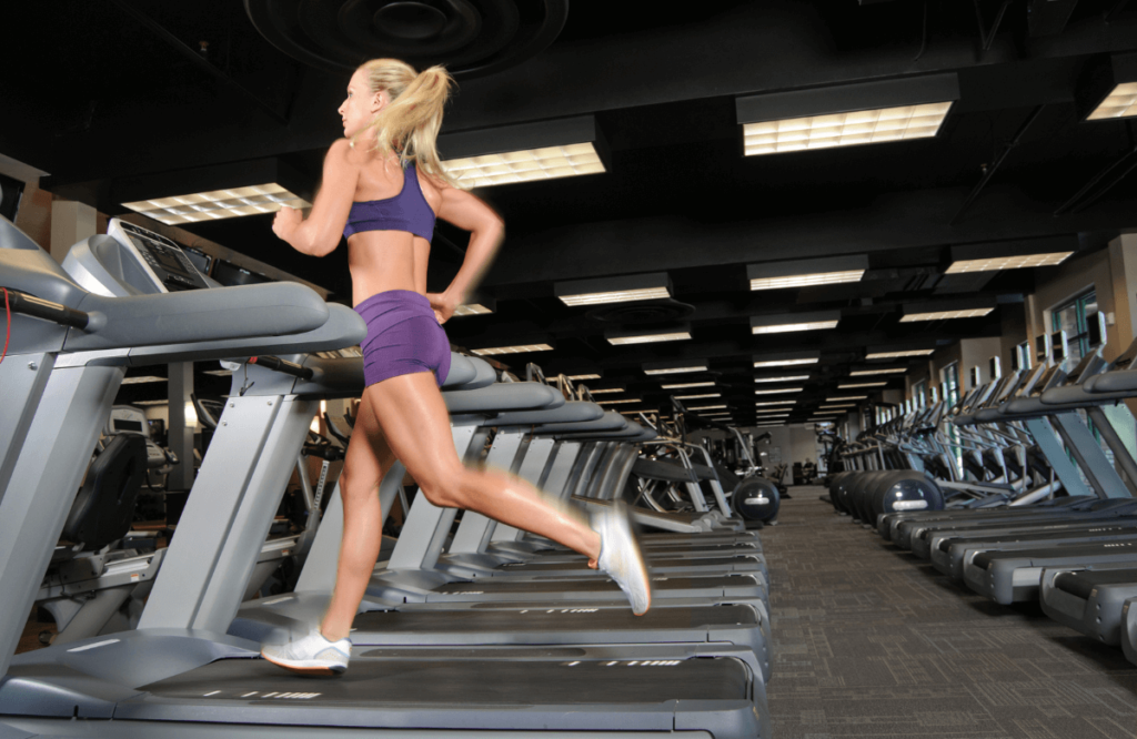A woman at the gym running on a fast treadmill