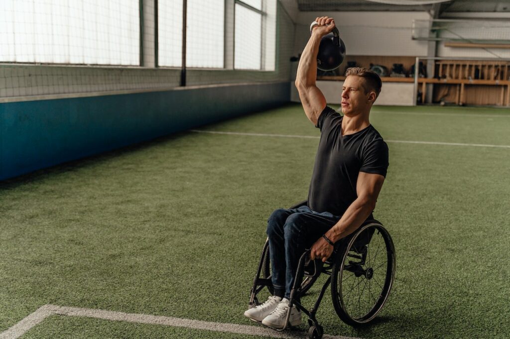 A man in a wheelchair doing the kettlebell press exercise