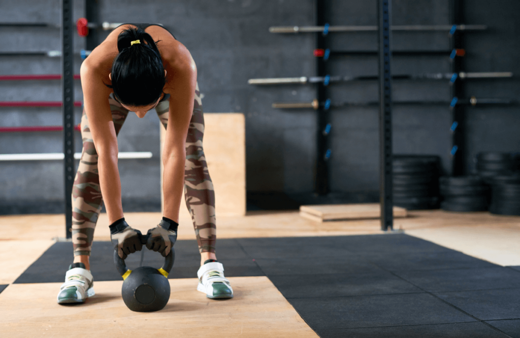 A woman at the gym doing the kettlebell halo exercise