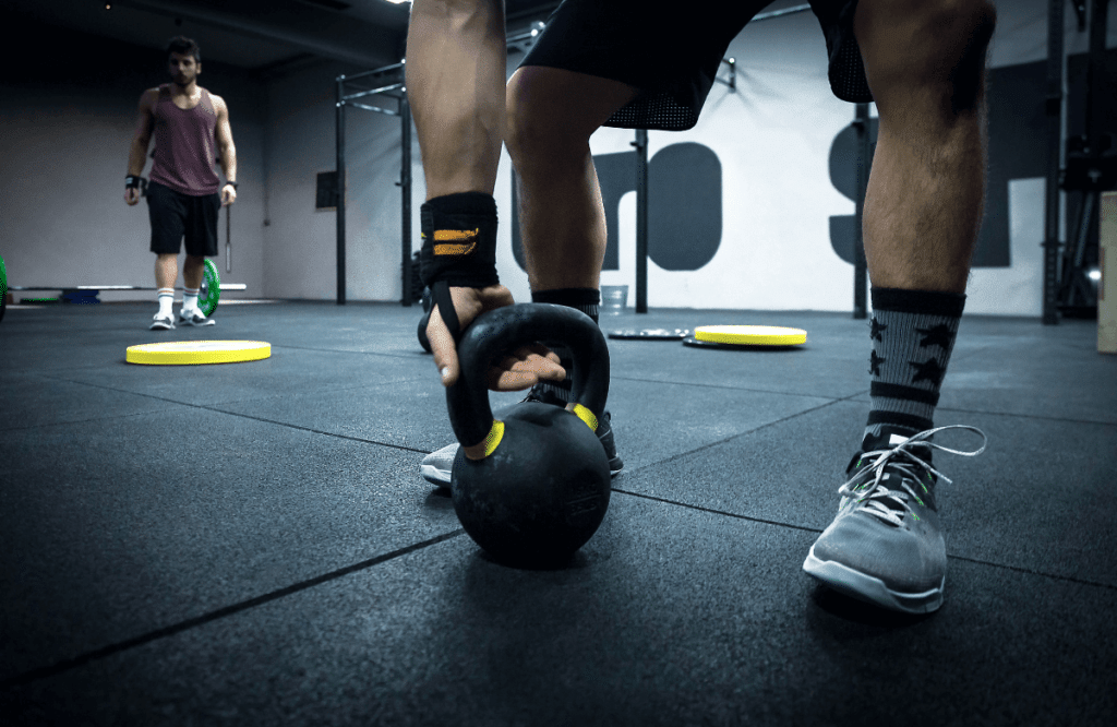 A man at the gym handling his kettlebell before doing the kettlebell halo exercise