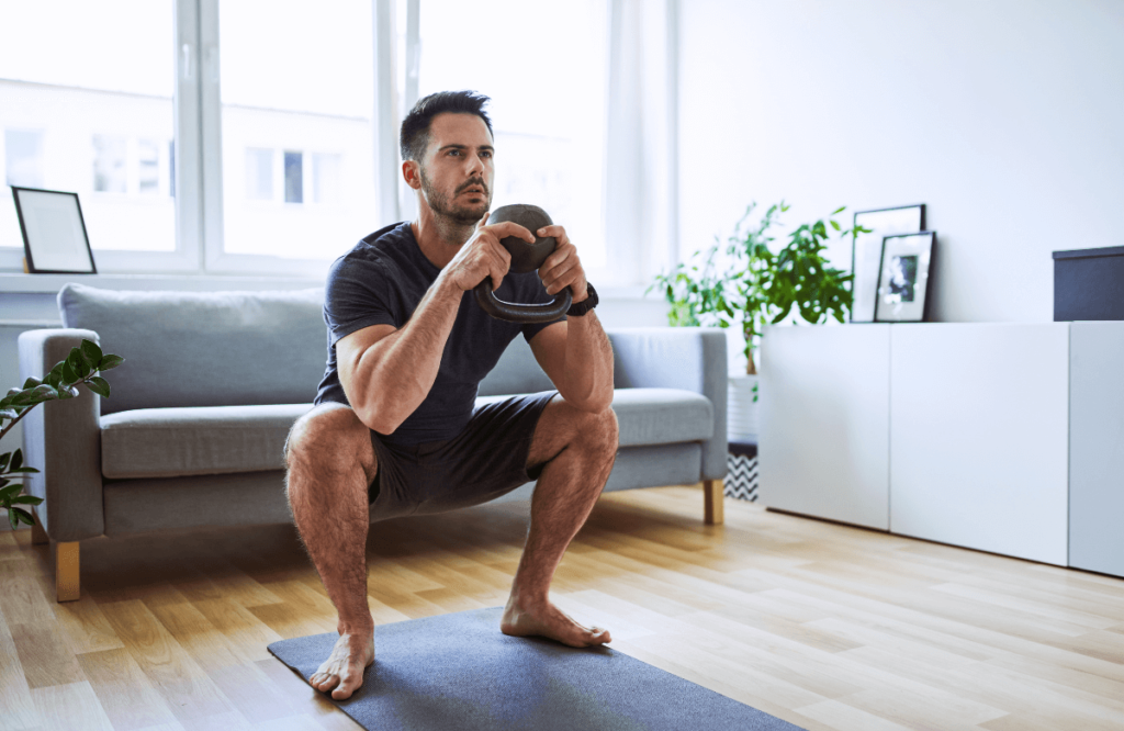 A man doing kettlebell goblet squats at home