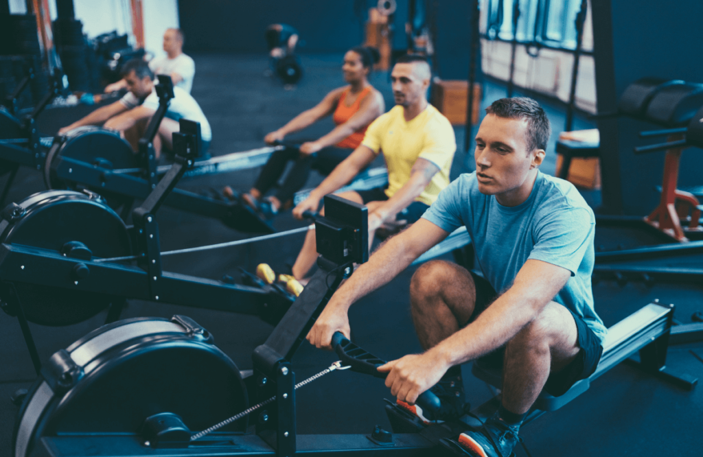 A group of people at the gym using rowing machine accessories for their training