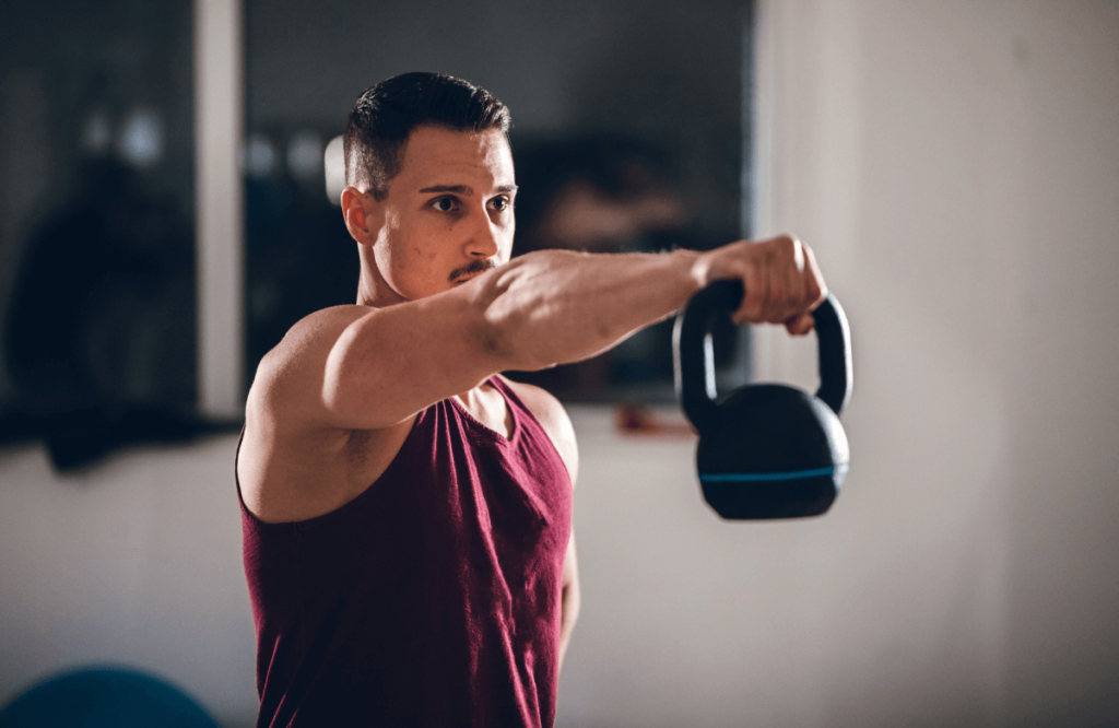 A man doing one arm kettlebell swing at home