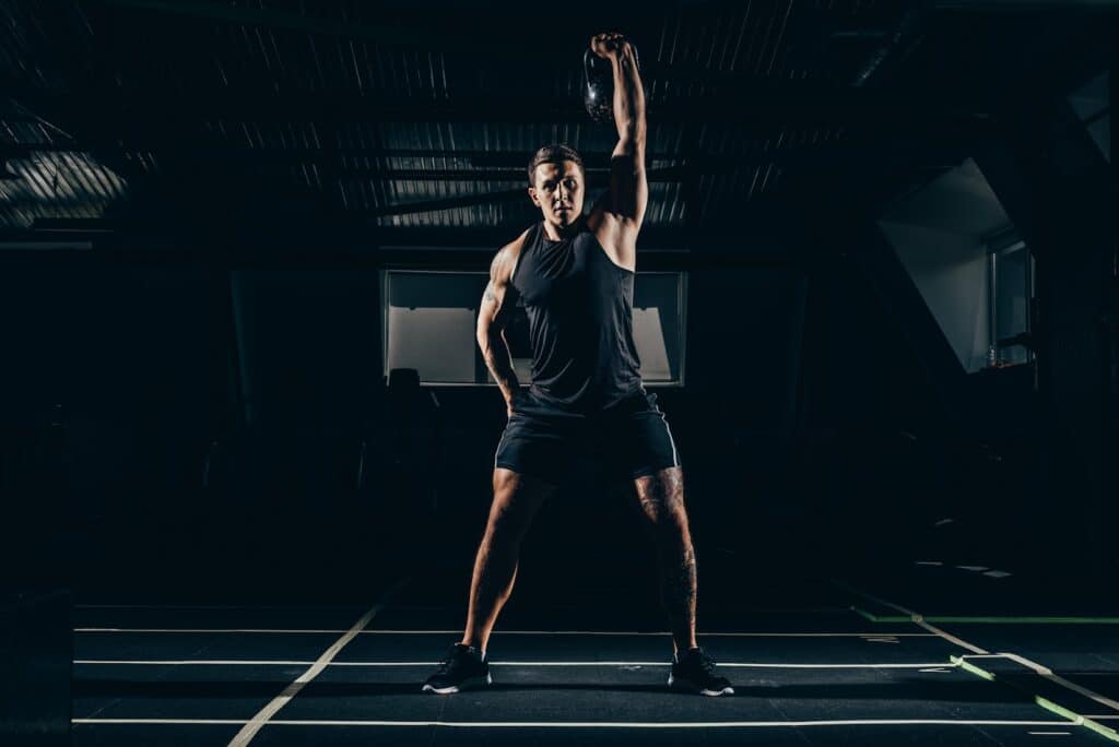 A man at the gym doing the kettlebell thruster exercise