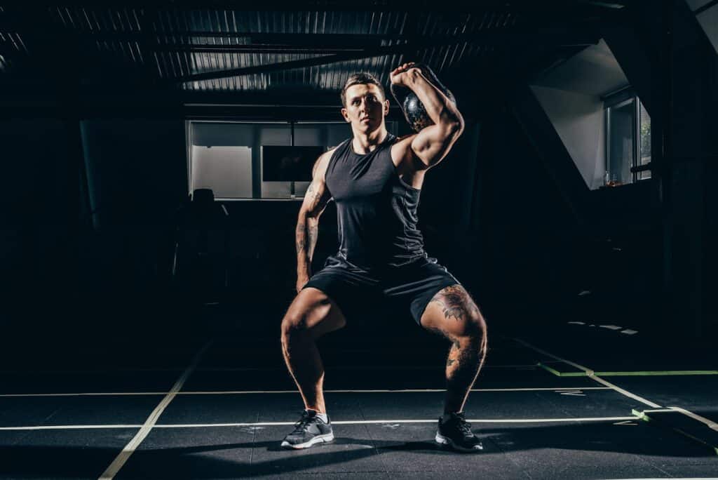 An athlete at the gym doing a kettlebell thruster workout