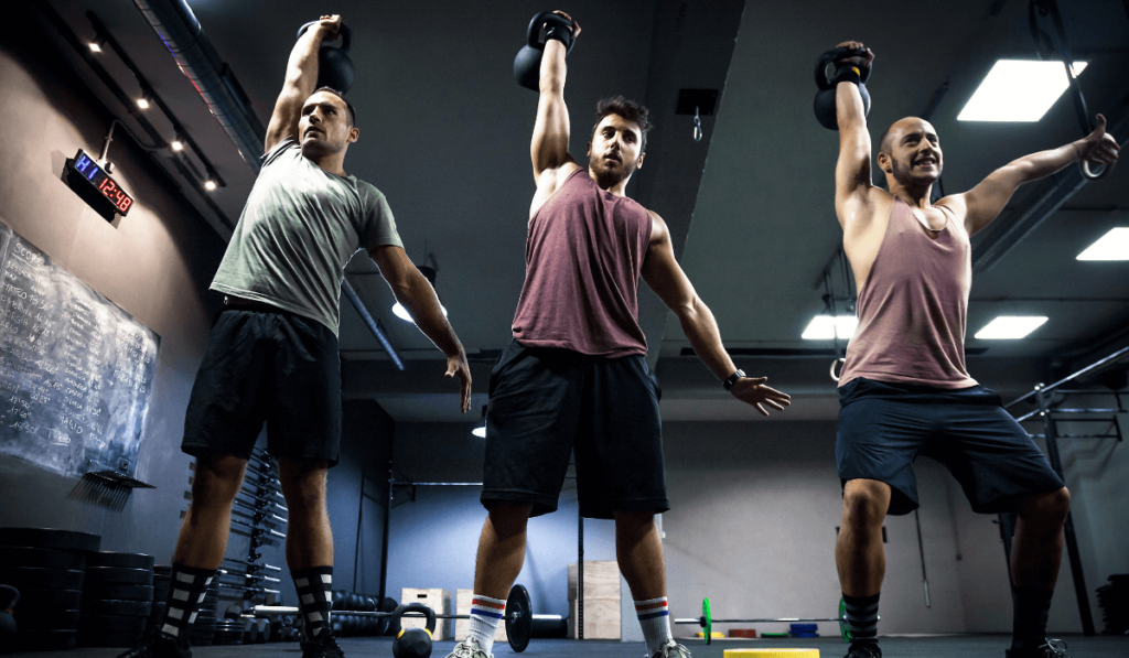 A group of people training at the gym doing one arm kettlebell swings
