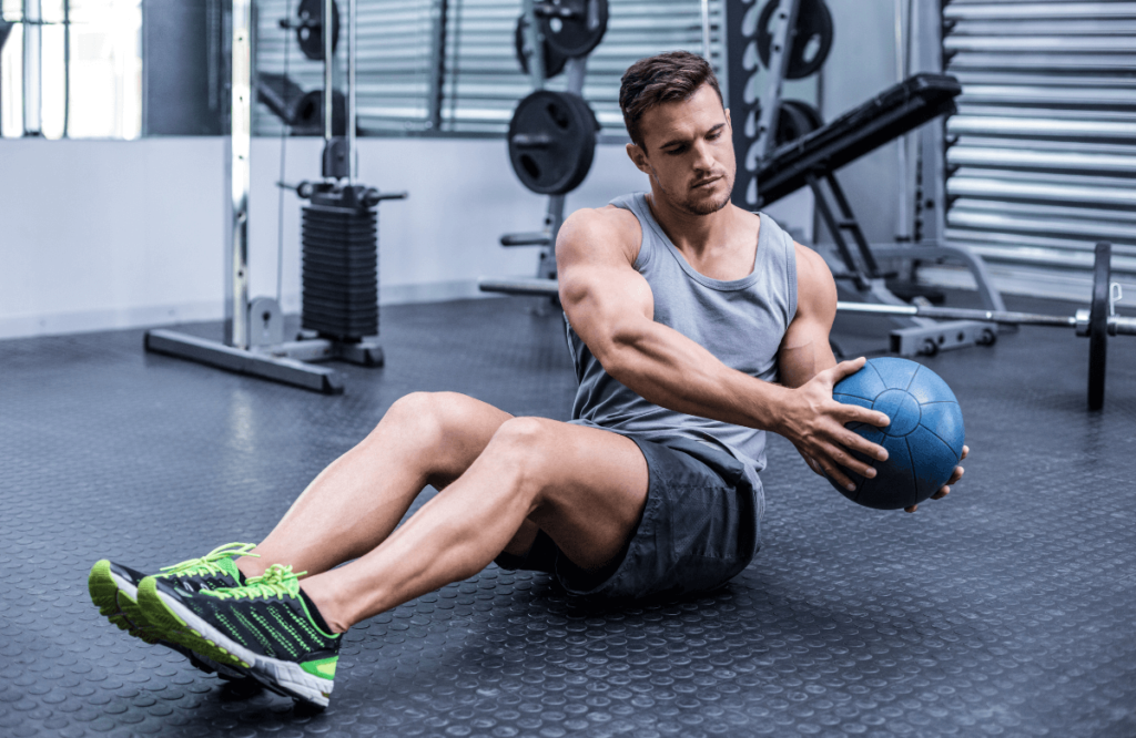 A man doing russian twists with a kettlebell at the gym