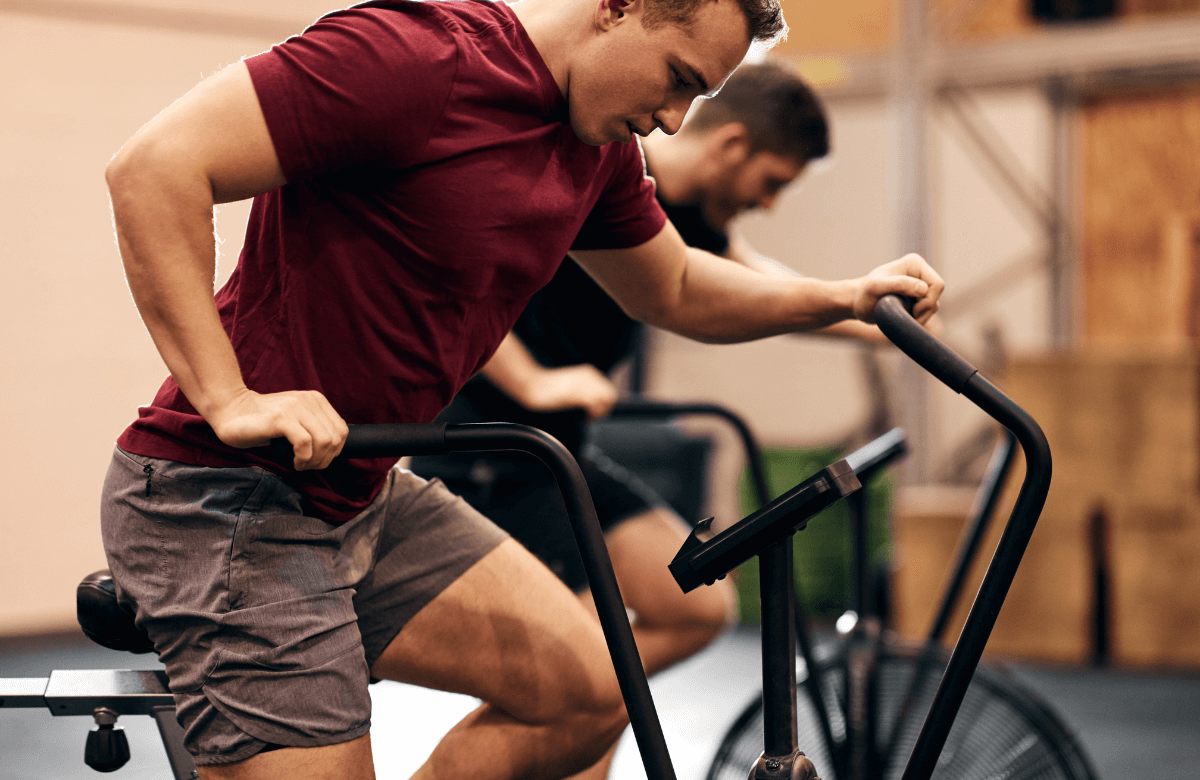 Two men at the gym trying the elliptical vs bike comparison