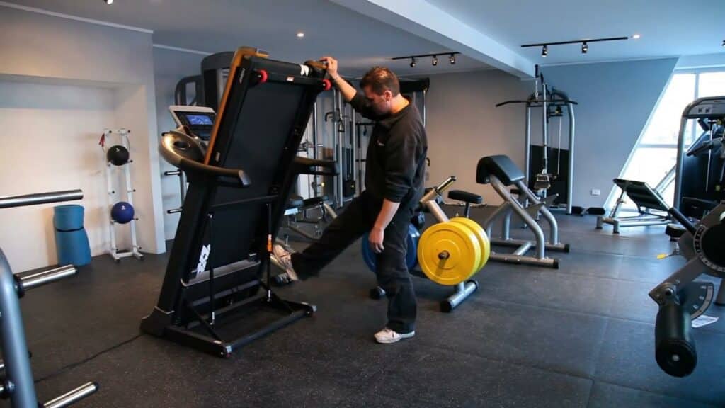 A man folding up a treadmill and before moving it