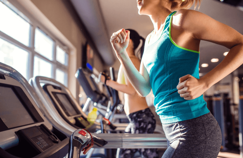 Two women at the gym performing a treadmill marathon