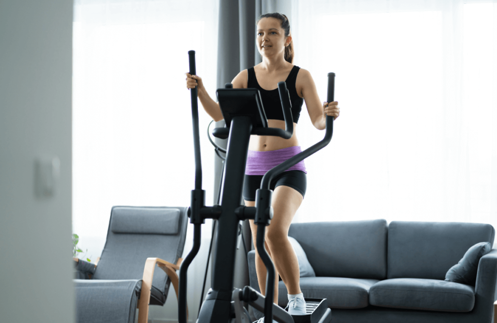 A woman at home knowing on long on an elliptical is required to see results