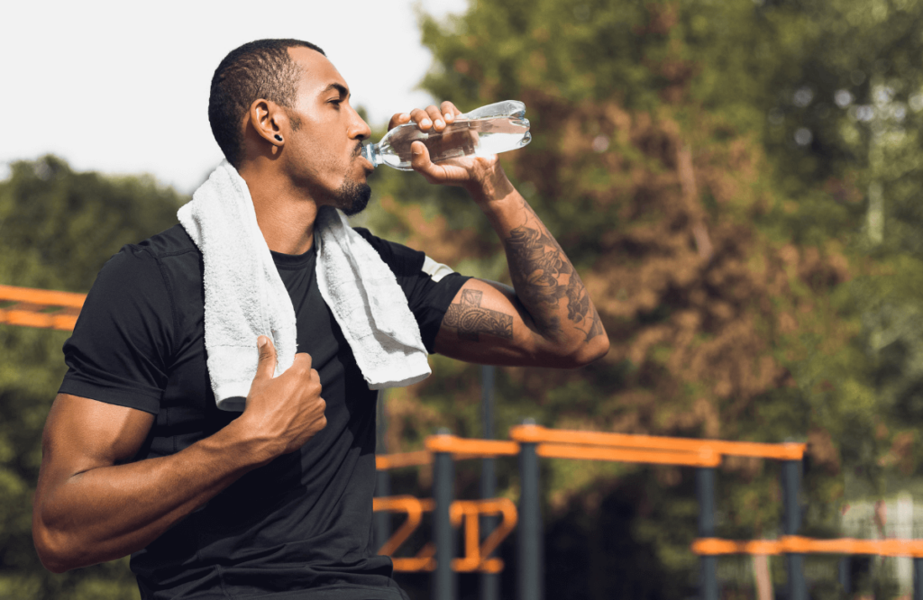 A man drinking water during his workout to lose fat and gain muscle