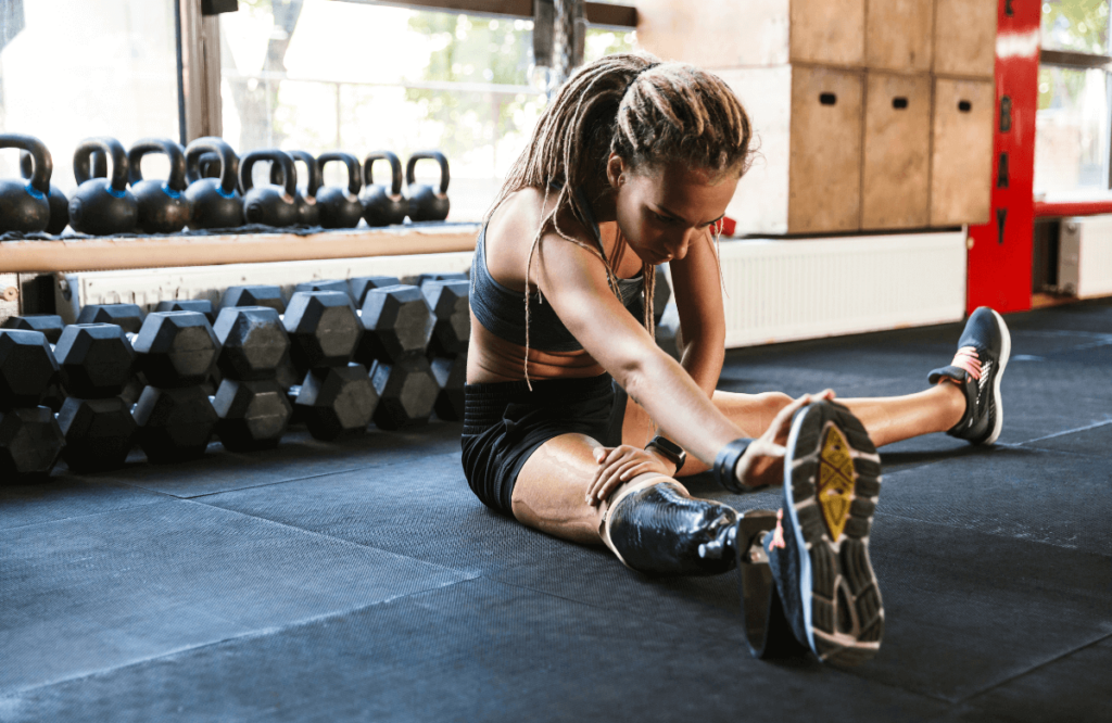 A muscular woman stretching at the gym to build muscle