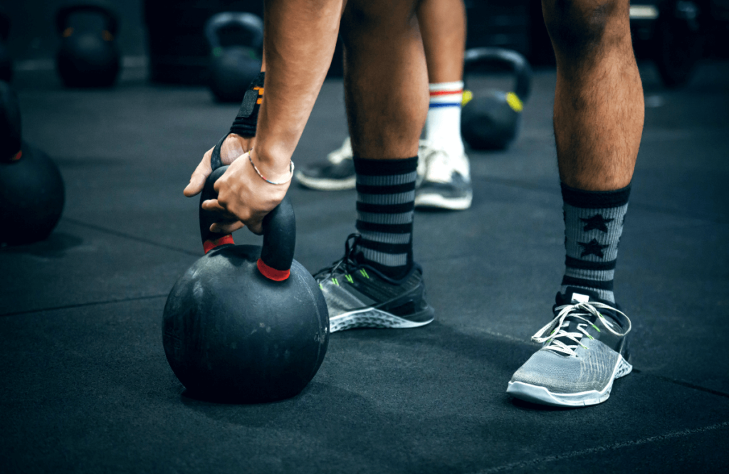 Someone preparing himself to do kettlebell high pulls, showing muscles worked