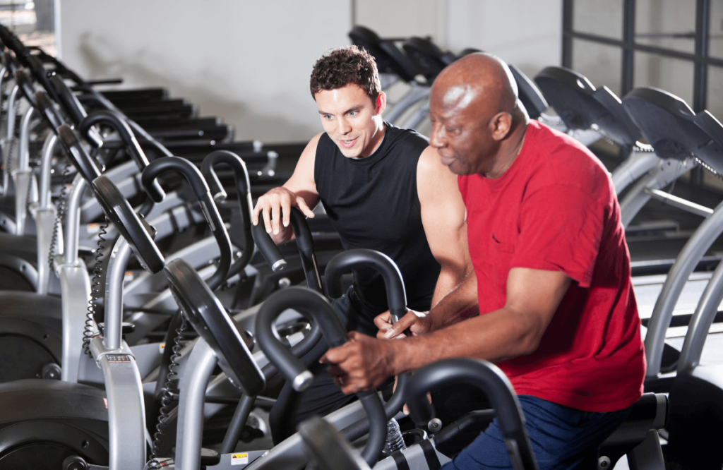 A man being coached on how to burn belly fat on the elliptical