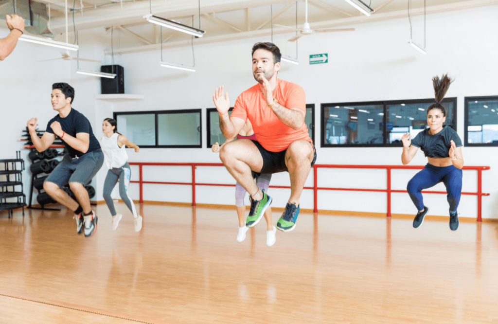 Un groupe d'entrainement réalise des tuck jumps (exercice de pliométrie) dans une salle de sport