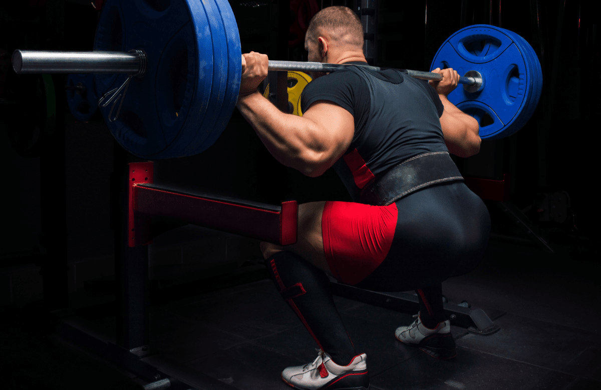 An athlete doing squats with a bar wearing the best deadlift belt