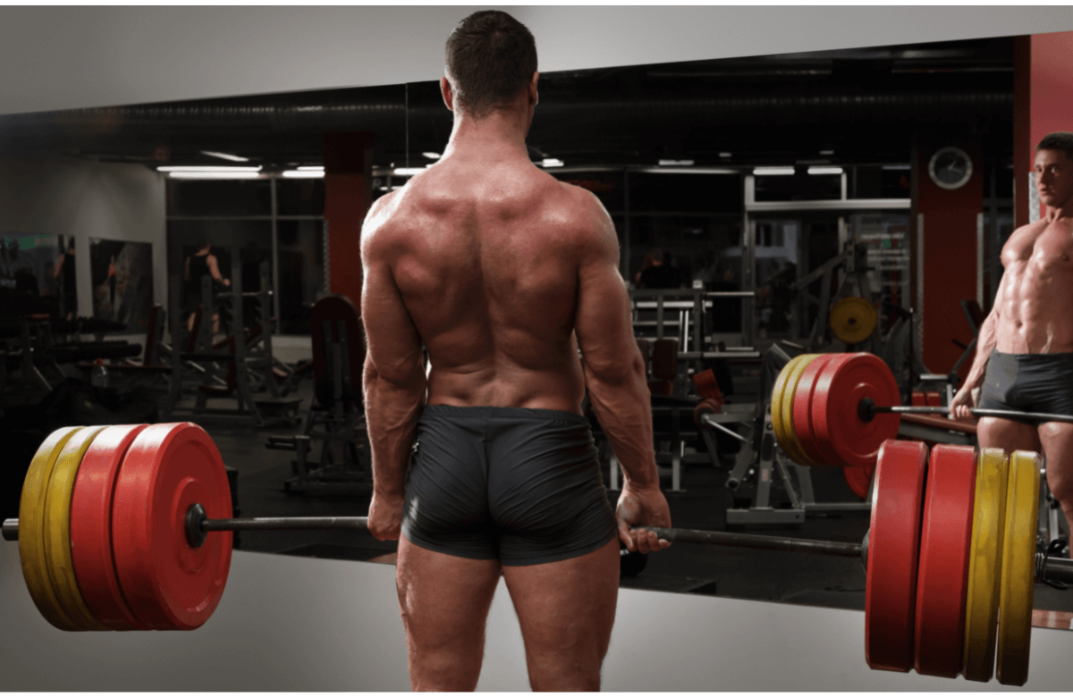 Un homme sollicite ses muscles en faisant un deadlift dans une salle de sport