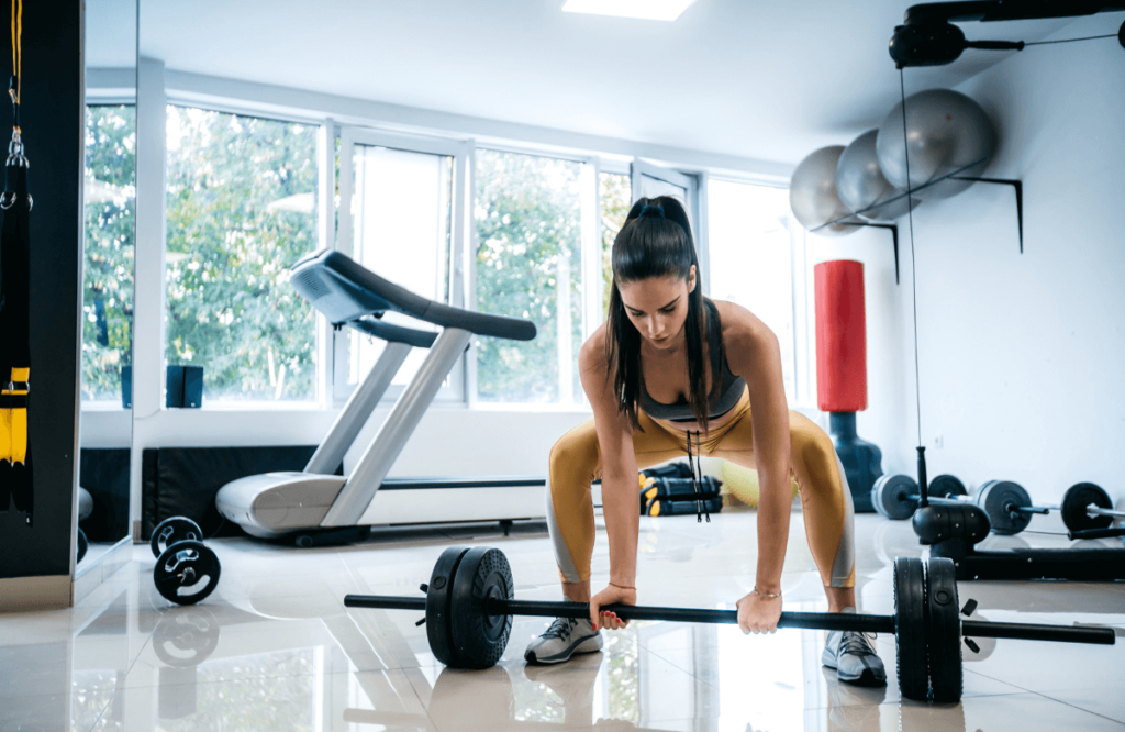 A woman performing deadlifts while pregnant in her home gym