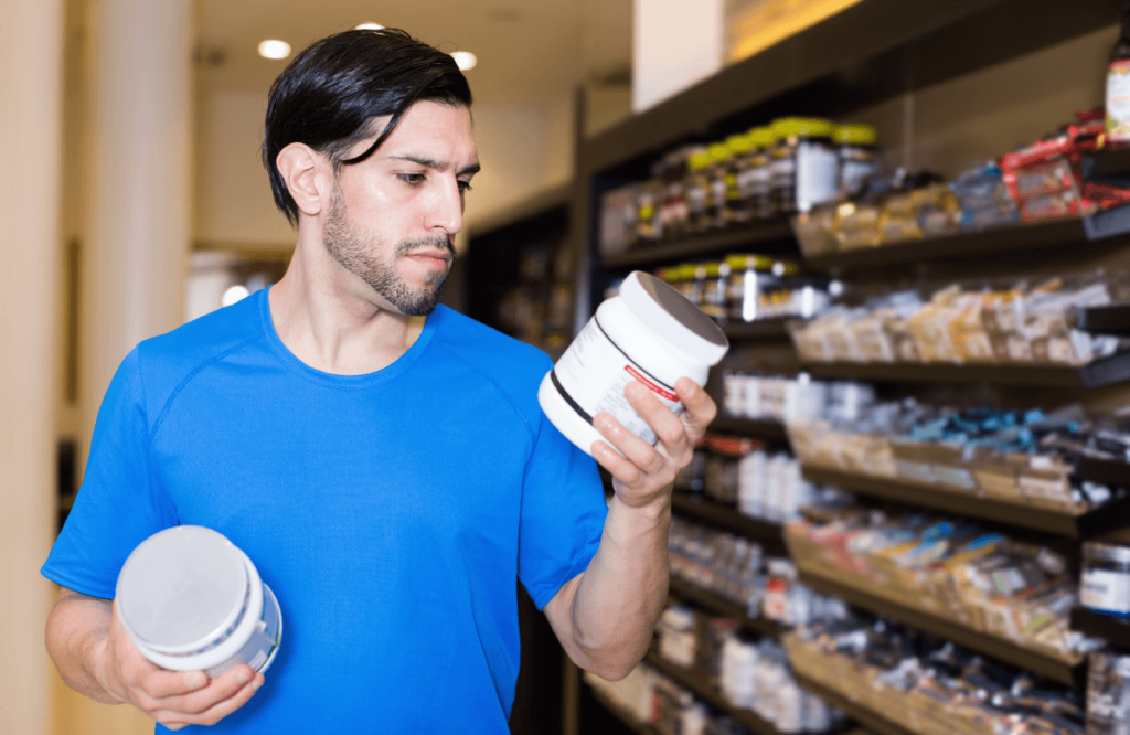 A man hesitating between two pre-workout supplements