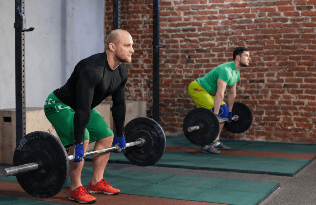 Two men at the gym deadlifting during their German volume training plan