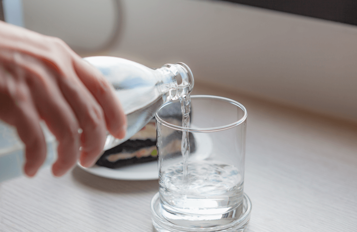 A woman drinking a cup of water during water fasting