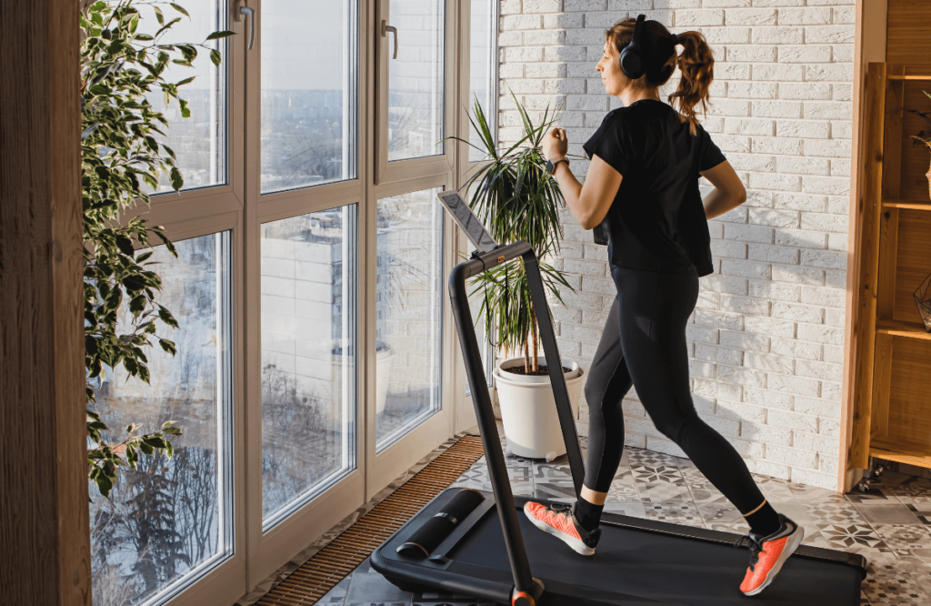 A woman running on the best treadmill under $1000 at home wearing headphones