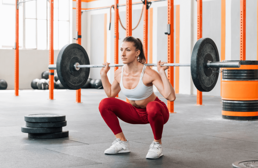 A woman at the gym doing squats to show the central knurling of a stiff bar