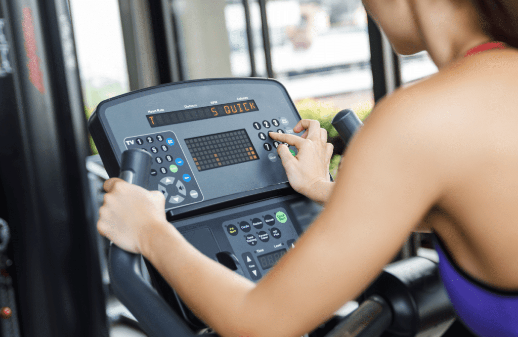 A woman using the handbars of her Peloton machine