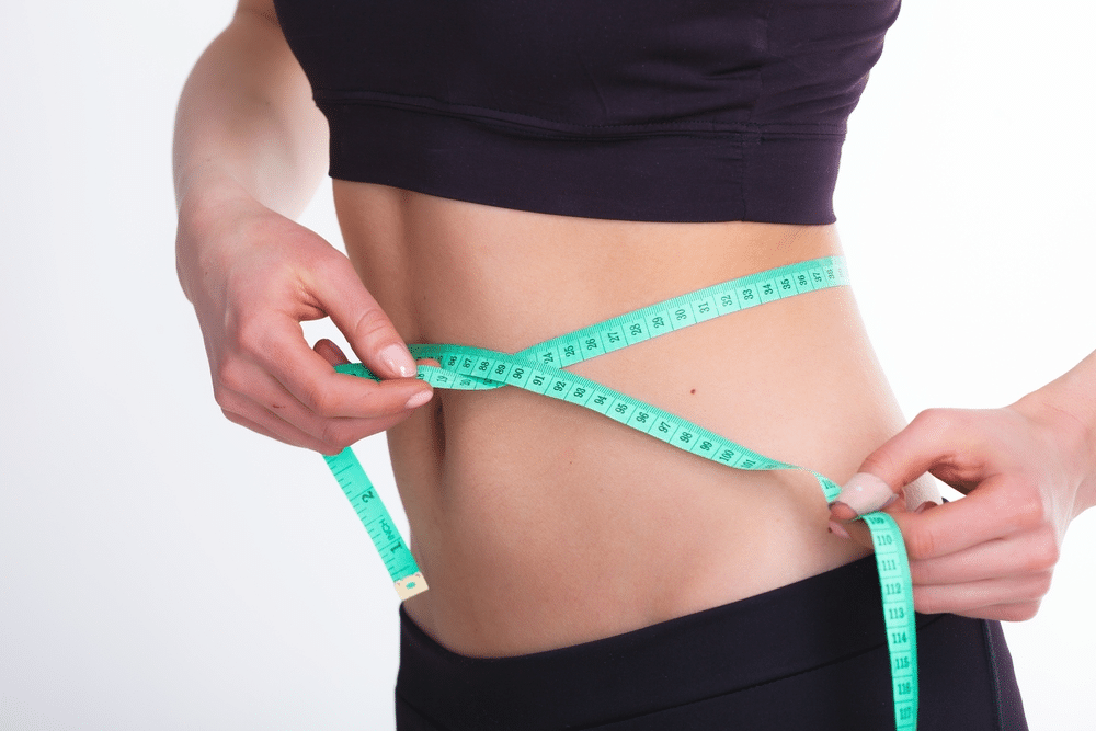 A woman measuring her waist to see if she has the average waist size for women