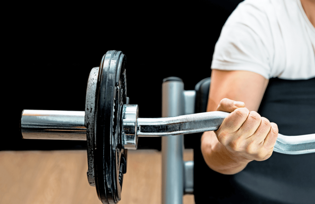 A man doing spider curls with an EZ bar