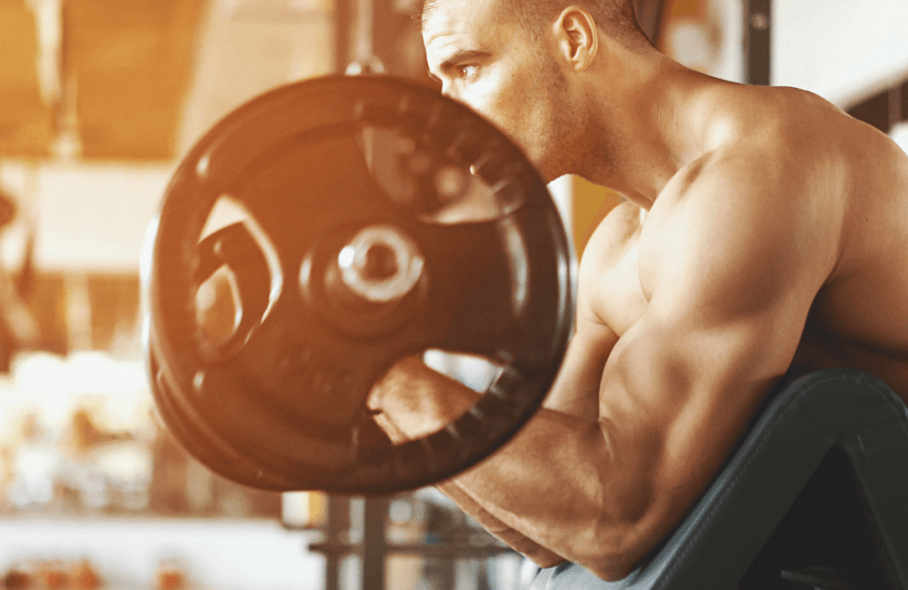 A man performing spider curls at the gym