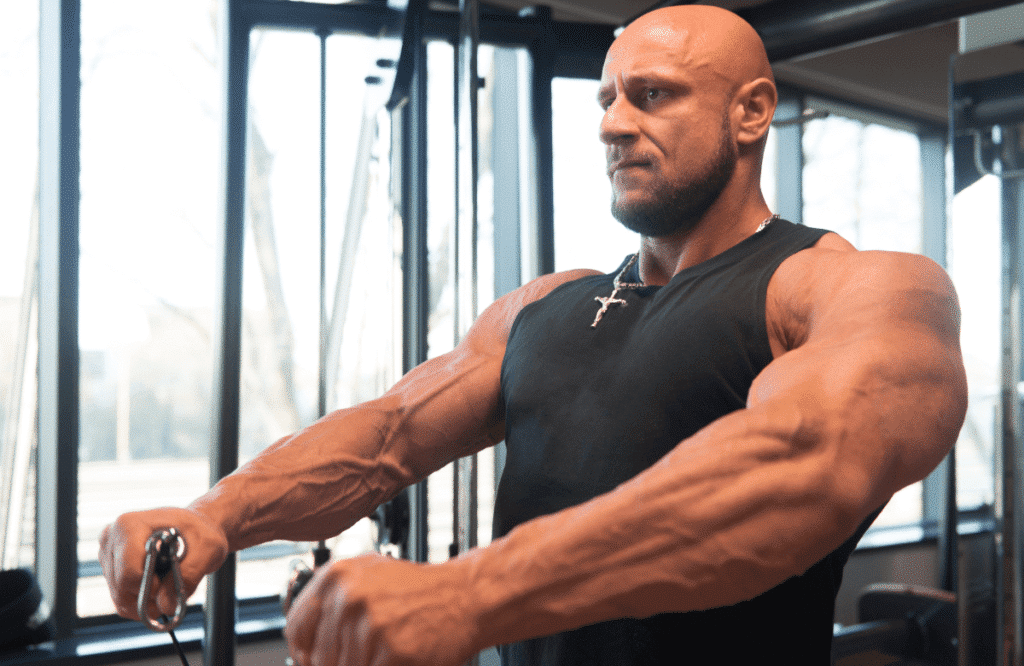 A strong man doing cable shoulder workouts