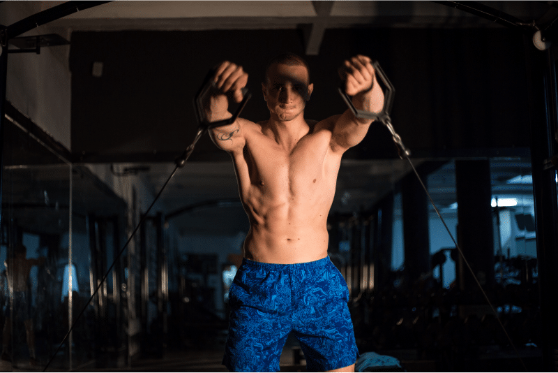 A man performing cable shoulder workouts at the gym