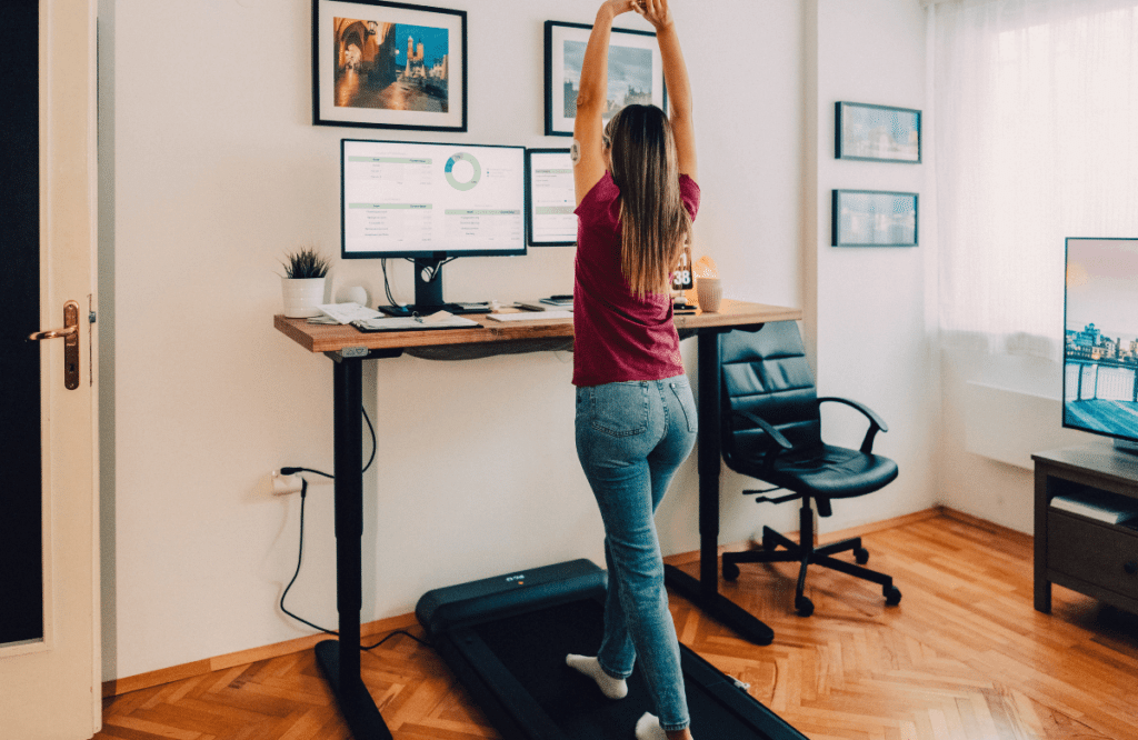 A woman working at home stretching on the best under-desk treadmill