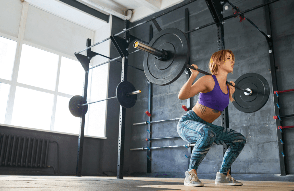 A woman doing squats in an empty gym