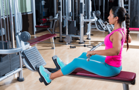 A woman using a low row machine at the gym