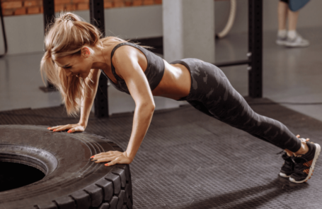 A woman performing press-ups at the gym on a tire