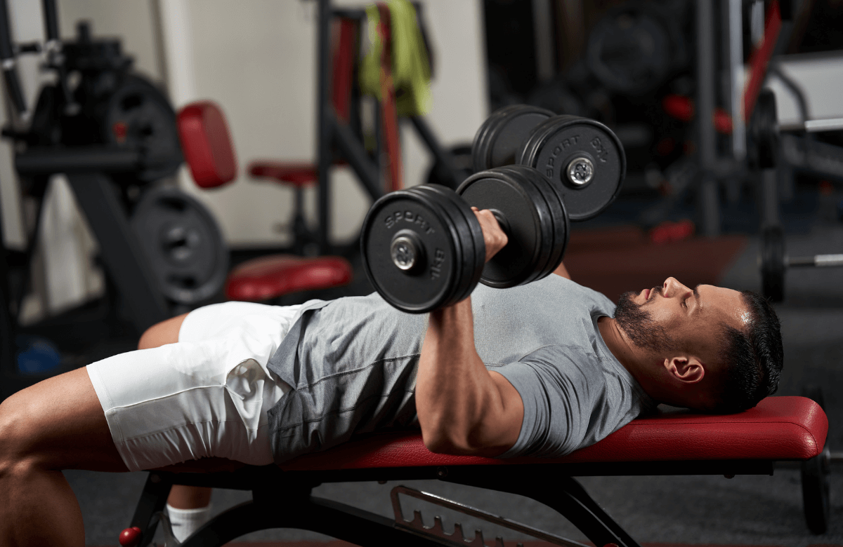 A man doing skull crushers with dumbbells
