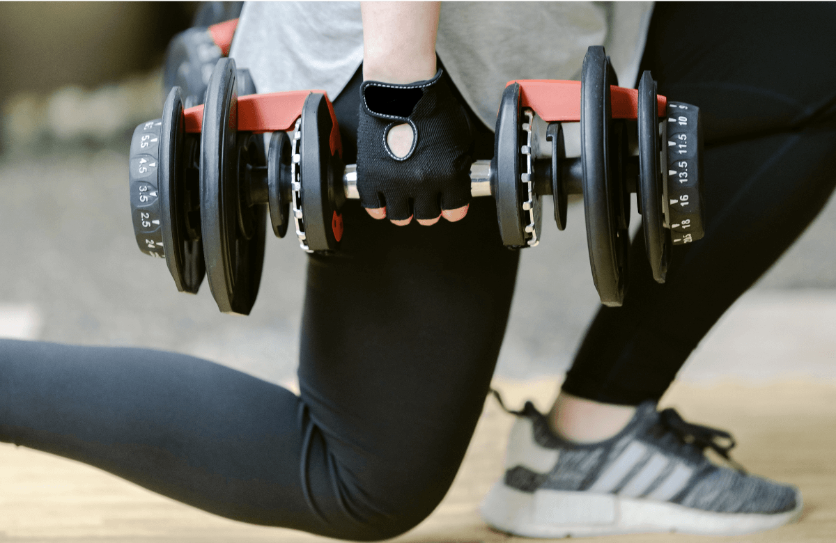 A woman using one of the best adjustable dumbbells available