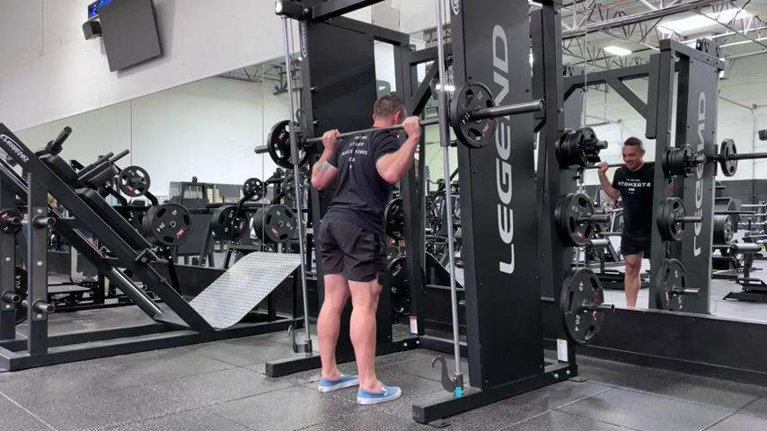 An athlete doing smith machine good mornings