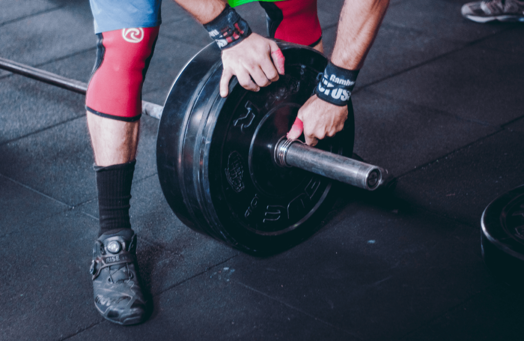 A man adding bumper plates to a barbell before lifting