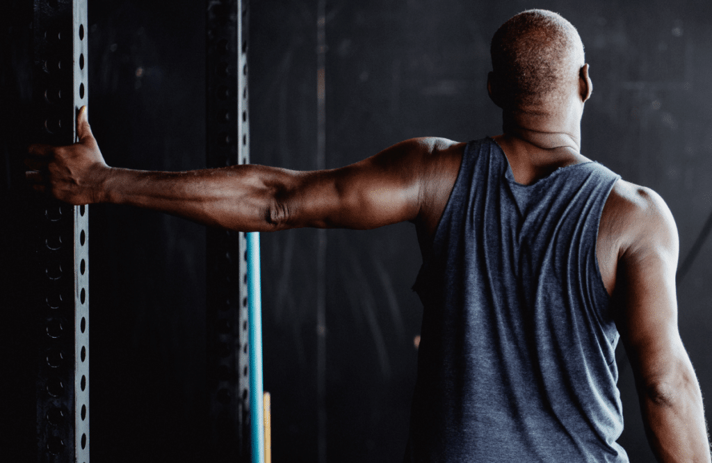 A strong man doing shoulder stretches at the gym