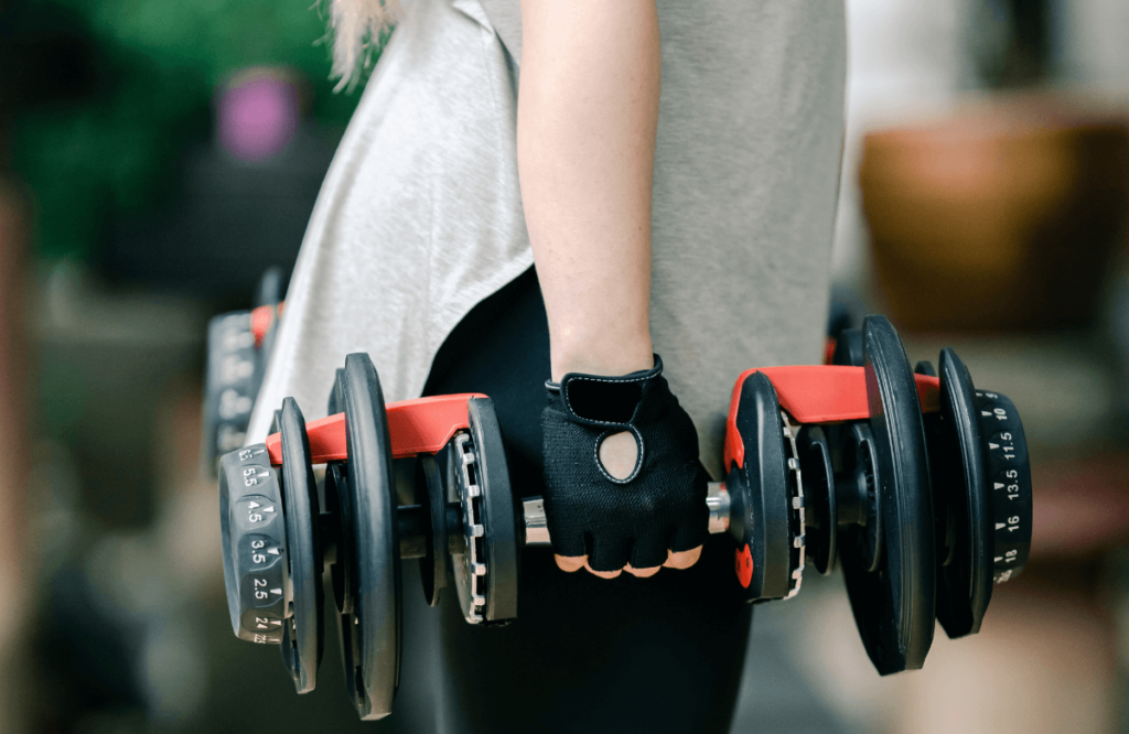A woman using the best adjustable dumbbells