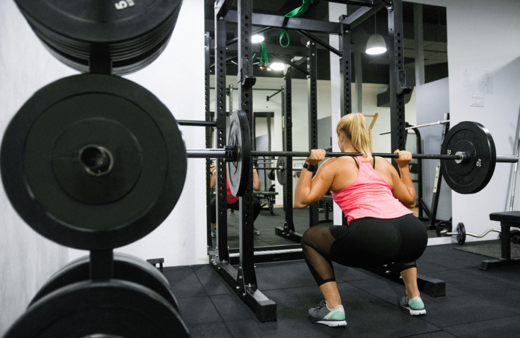 A woman using a folding squat rack at the gym
