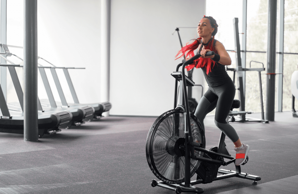 A woman using an Assault Bike in an empty gym